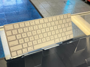 Metallic keyboard on a stand with a reflective surface background