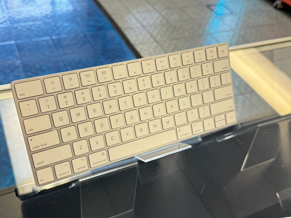 Metallic keyboard on a stand with a reflective surface background