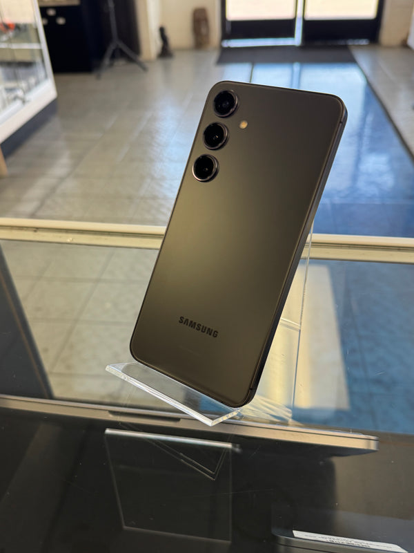 Samsung smartphone held against a reflective surface with a blurred indoor background