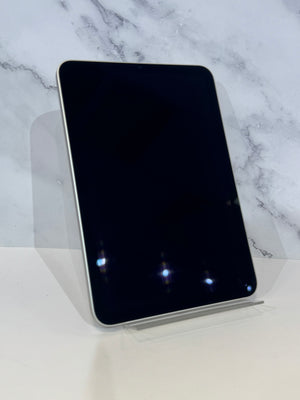 A black tablet with rounded corners and a silver edge, displayed upright on a clear acrylic stand against a white marble-patterned background.