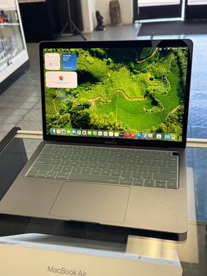 Laptop with screen showing a nature-themed wallpaper on a glass surface.