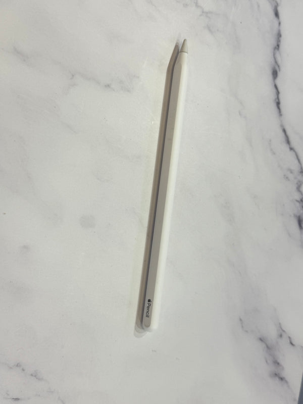 A white Apple Pencil with a silver tip lies diagonally on a white marble surface.