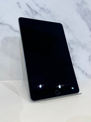 A black tablet device with rounded corners, standing upright on a clear acrylic display stand against a white marble-patterned background.
