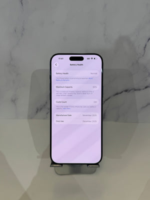 A black smartphone displayed upright on a small stand against a light marble-patterned background, with the screen showing battery health details.