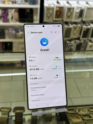 Samsung smartphone showing device care settings on the screen, displayed upright on an acrylic stand in a store setting