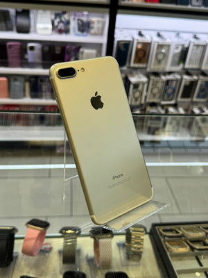 Gold iPhone 7 Plus held up against a store window display.