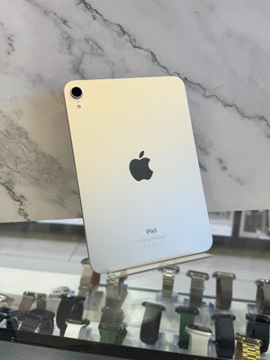 An Apple iPad with a light gold back panel, standing on a display stand in front of a white marble-patterned background.