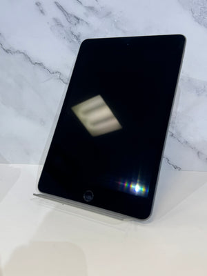 A black tablet device with rounded corners, standing upright on a clear display stand against a white marble-patterned background.