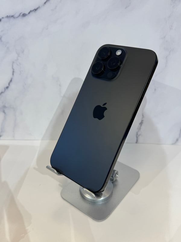 A black Apple iPhone 12 Pro shown from the back, resting on a silver metal stand against a white marble-patterned background.