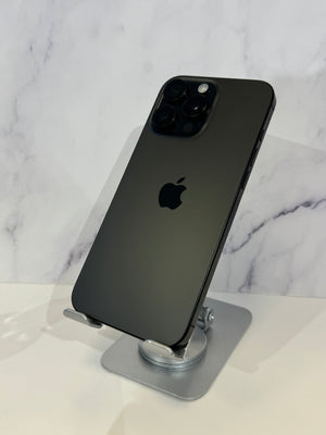 A black Apple iPhone 12 Pro shown from the back, resting on a silver metal stand against a white marble-patterned background.