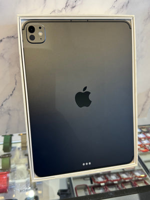 A black Apple iPad shown from the back inside its white retail box, with the Apple logo centered on the back panel.