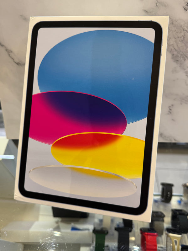 An Apple iPad in its white retail box, showing the colorful abstract wallpaper on the screen, photographed on a glass display counter with a marble-patterned background.
