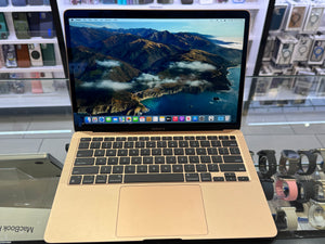 Gold MacBook Pro laptop with mountainous landscape on screen in a store setting