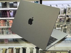 Gray laptop with Apple logo on a glass display table