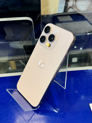 A white iPhone shown from the back, resting on a clear acrylic display stand against a blue surface.