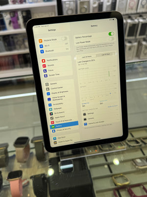 Tablet displaying a settings menu with a blurred background of electronic equipment.