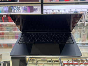 A black laptop shown open on a retail display counter with shelves of accessories in the background.