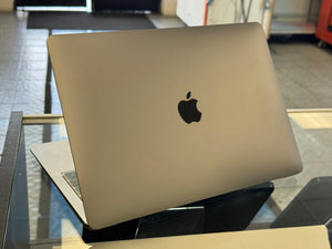 Apple laptop on a glass surface with a blurred indoor background