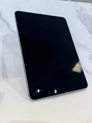 A black tablet with a glossy screen, standing upright on a clear display stand against a white marble-patterned background.