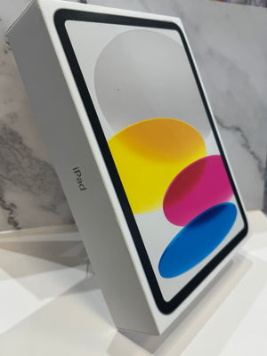 A white Apple iPad box standing upright on a white surface, with the iPad screen artwork visible. The side of the box shows the text 'iPad'.