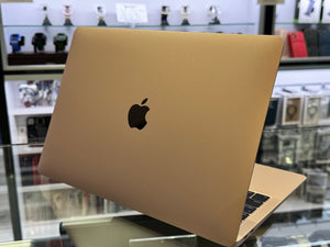 Gold laptop with Apple logo on a glass surface in a store setting