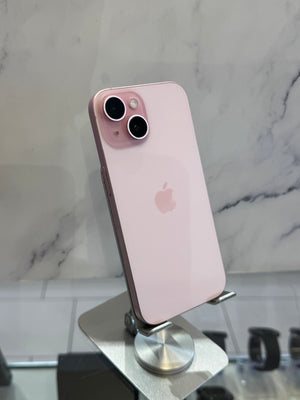 A light pink Apple iPhone with a dual-camera setup, displayed on a silver stand against a white marble-patterned background.
