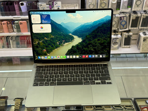 Laptop displaying a mountainous landscape on a glass surface with electronic devices in the background