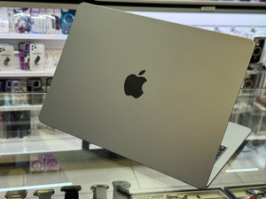 Silver laptop with Apple logo on a glass surface in a store setting