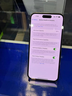 Smartphone displaying battery health and charging settings on a reflective surface