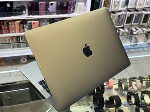Laptop with Apple logo on a glass display table in a store.