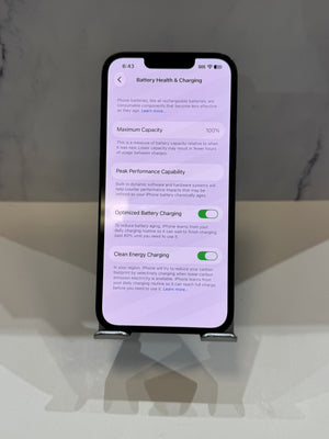 A smartphone displayed upright on a small stand, showing the Battery Health & Charging settings screen on a light gray background.