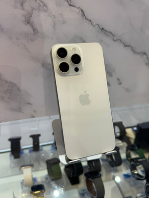 A silver Apple iPhone Pro showing its back panel with three rear cameras, displayed on a stand in front of a marble-patterned background.