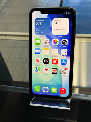 Smartphone with app icons displayed on a stand in front of a window
