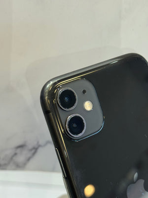 Close-up of the rear upper portion of a black smartphone showing the dual camera lenses and flash, photographed against a light marble-like background.