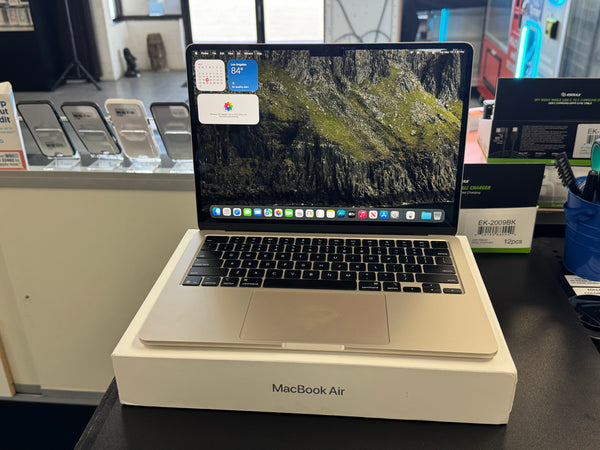 MacBook Air laptop on display with a mountainous screen saver in a store setting.