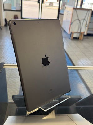 Back view of an Apple device on a reflective surface with a blurred indoor background