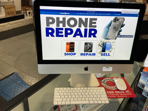 Computer monitor displaying a phone repair website on a desk.