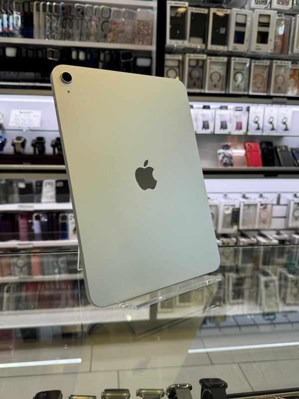 An Apple iPad shown from the back, featuring its signature silver aluminum finish and the central Apple logo, photographed in a retail store setting with display cabinets in the background.