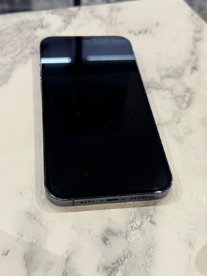A black smartphone with a glossy screen lies on a white and gray marble-patterned surface.