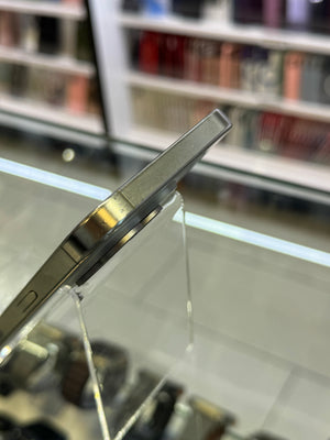 Close-up of a silver metallic smartphone edge resting on a clear acrylic display stand inside a retail store.