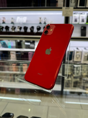 Red smartphone with Apple logo on a clear stand in a store setting