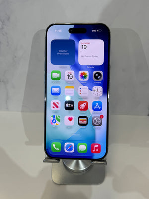 A black iPhone with its screen on, resting on a silver metal display stand against a light gray marble-patterned background.