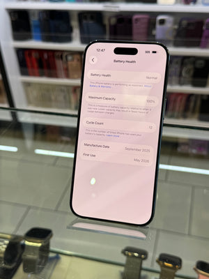 Smartphone displaying battery health screen on a glass surface with blurred background
