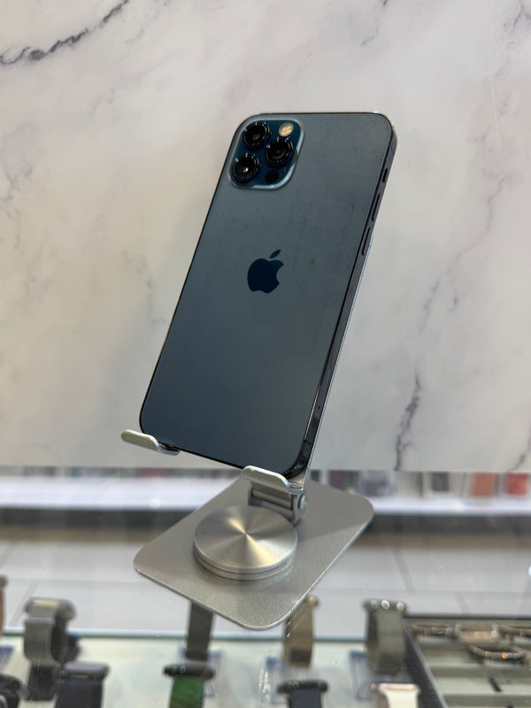 A dark blue-gray Apple iPhone Pro shown from the back, mounted on a silver magnetic stand on a white marble surface.