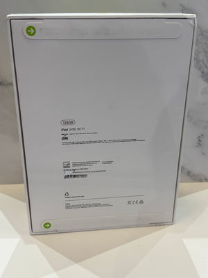 The back of a silver Apple iPad box, showing various regulatory markings, set against a light marble background.