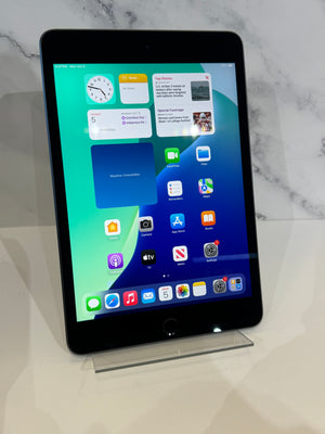 A black Apple iPad standing upright on a clear acrylic display stand against a white marble-patterned background.