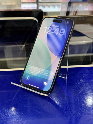 A black smartphone with a colorful lock screen wallpaper resting on a clear acrylic display stand over a blue surface.