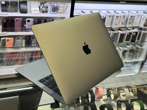 Gold Apple laptop on display in a store with phone cases in the background
