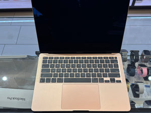 Gold MacBook Pro laptop on a reflective surface with blurred background