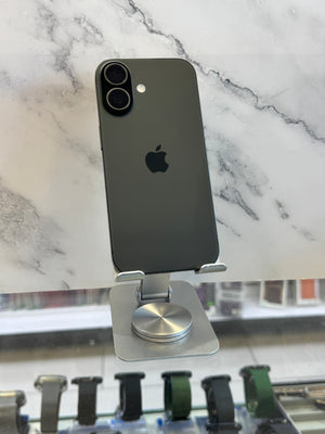 A dark gray Apple iPhone shown from the back, resting on a silver metal stand against a white marble-patterned background.